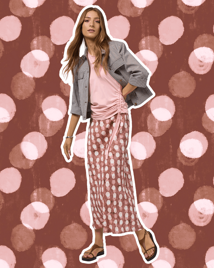 Madly Sweetly model in a pink midi skirt with allover white dot print and elastic gathered waist. On a studio background