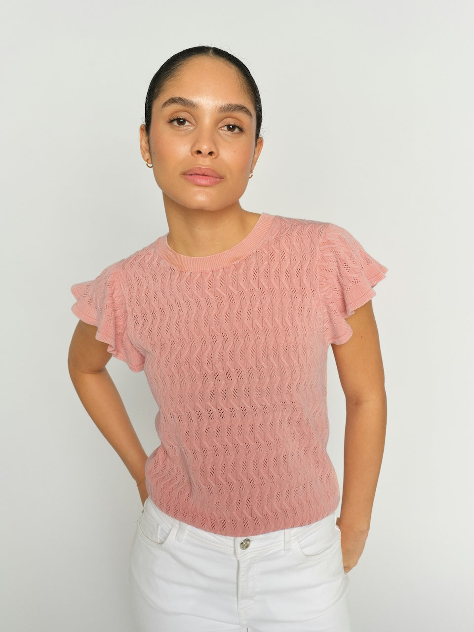Woman wearing a pink textured top against a plain background