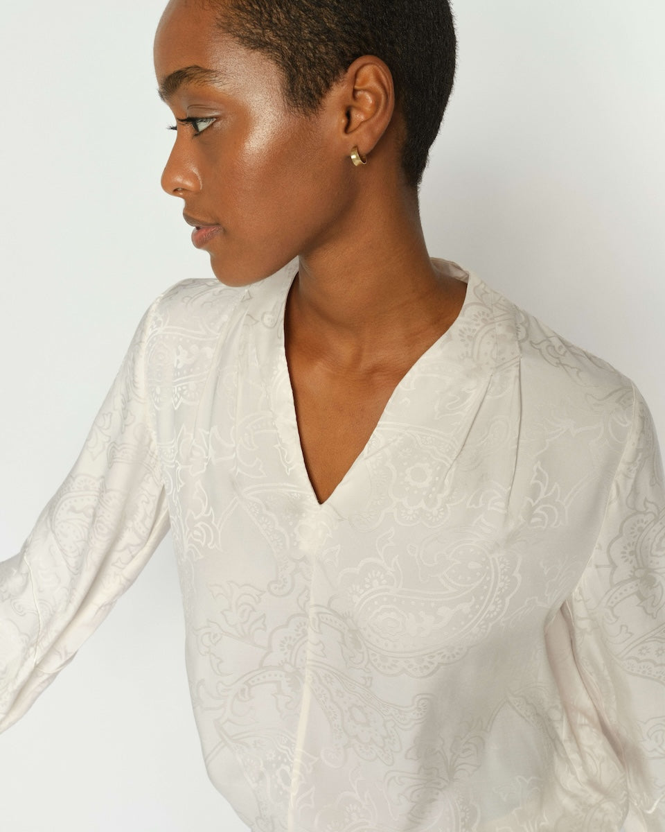 Woman wearing a white textured top against a plain background