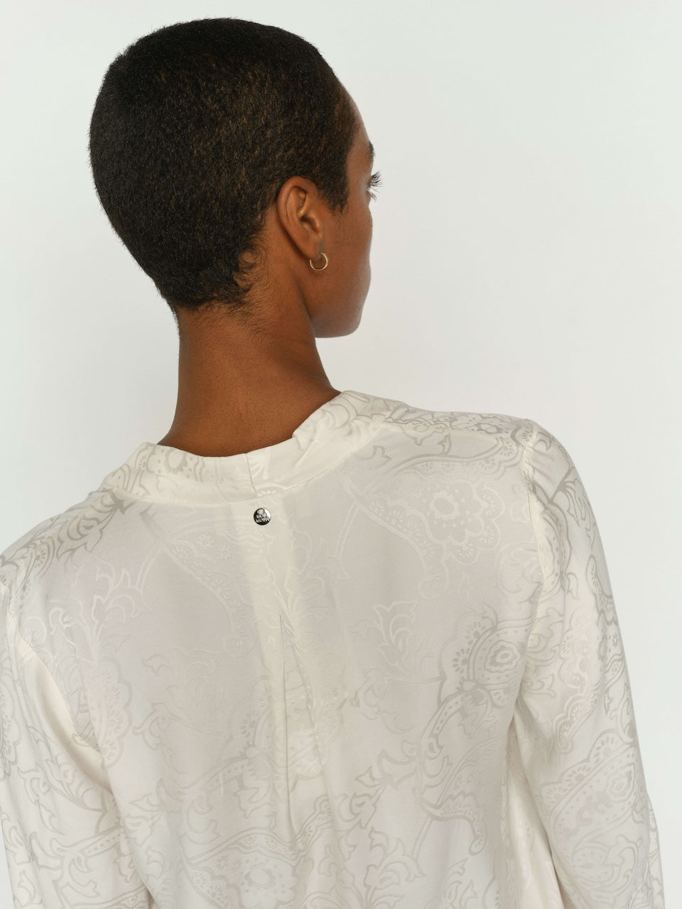 Ecru patterned blouse with button closure at back neckline