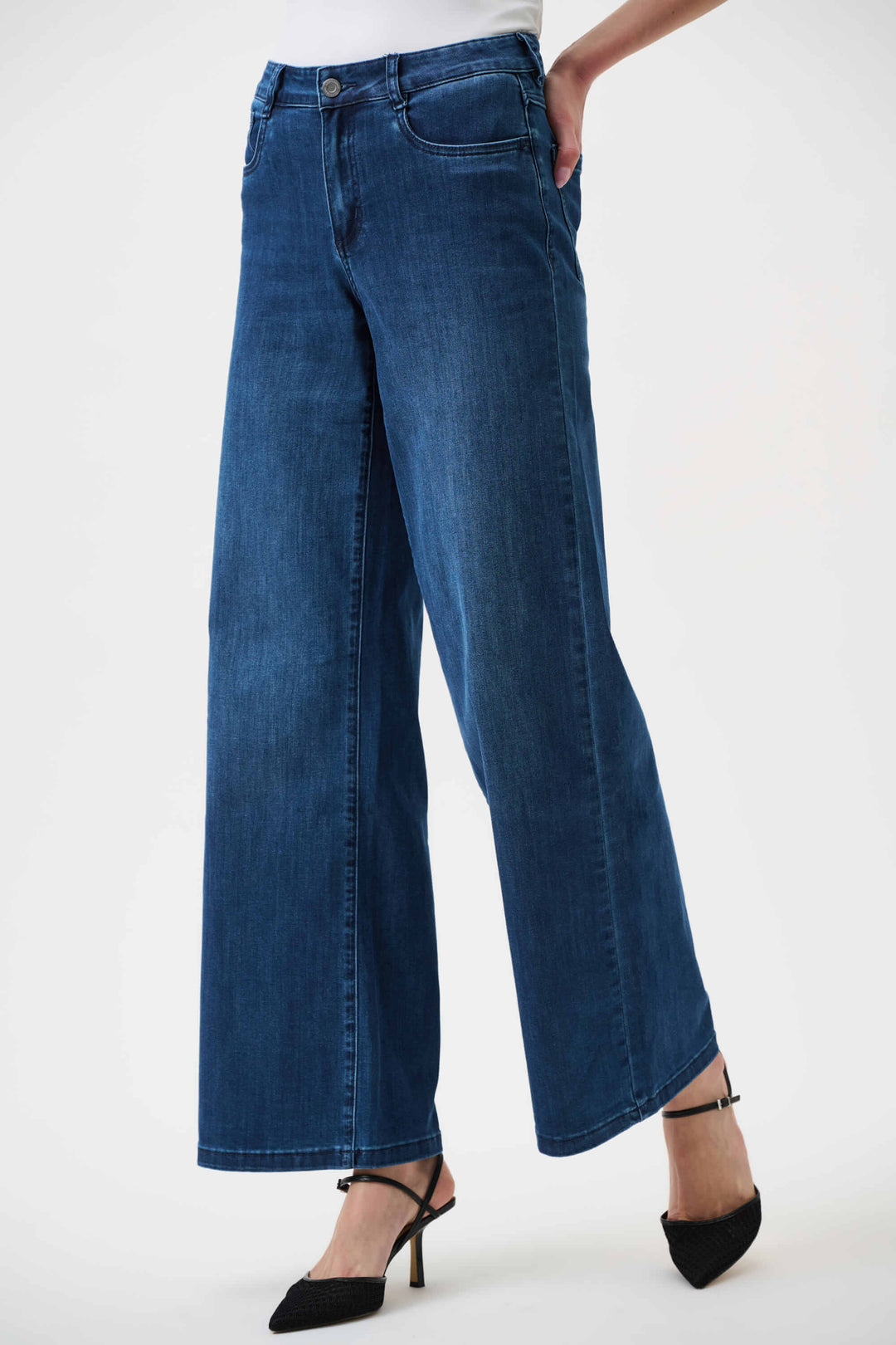 Joseph Ribkoff  model wearing a black long-sleeve open-front cardigan, blue wide-leg jeans, and black pointed-toe heels, standing against a plain white studio background.