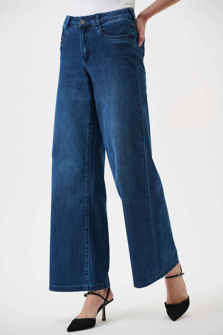 Joseph Ribkoff  model wearing a black long-sleeve open-front cardigan, blue wide-leg jeans, and black pointed-toe heels, standing against a plain white studio background.