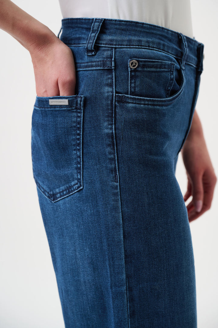 Joseph Ribkoff  model wearing a black long-sleeve open-front cardigan, blue wide-leg jeans, and black pointed-toe heels, standing against a plain white studio background. Close view 