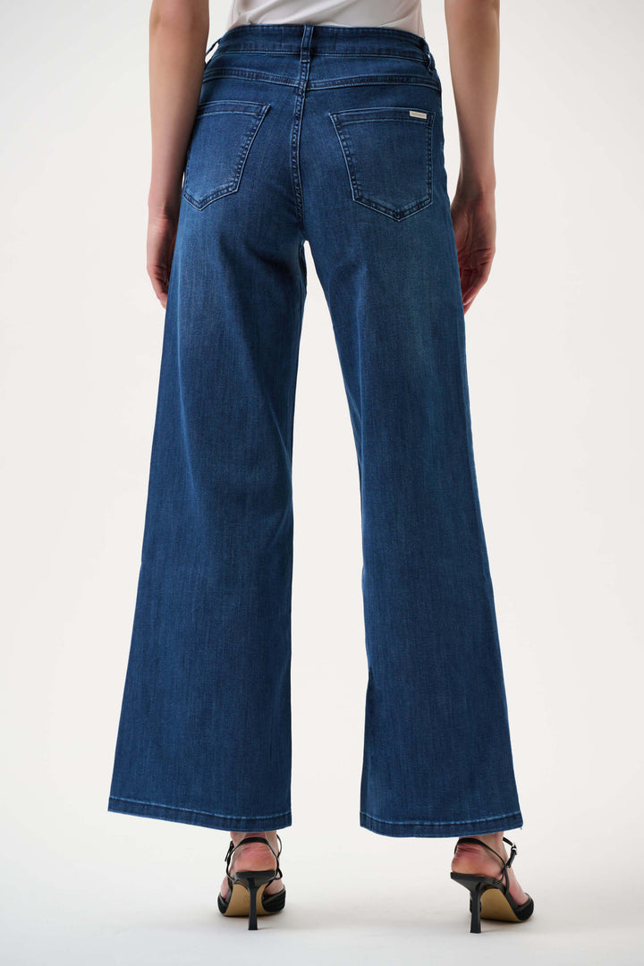 Joseph Ribkoff  model wearing a black long-sleeve open-front cardigan, blue wide-leg jeans, and black pointed-toe heels, standing against a plain white studio background. Back view 