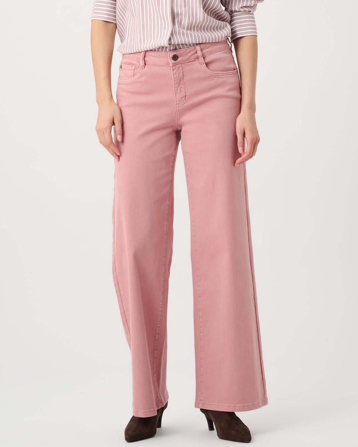 Joseph Ribkoff modeling a pink and white vertically striped button-down shirt with puffed sleeves, paired with dusty pink wide-leg pants and dark brown pointed-toe heels, against a plain light gray studio background.