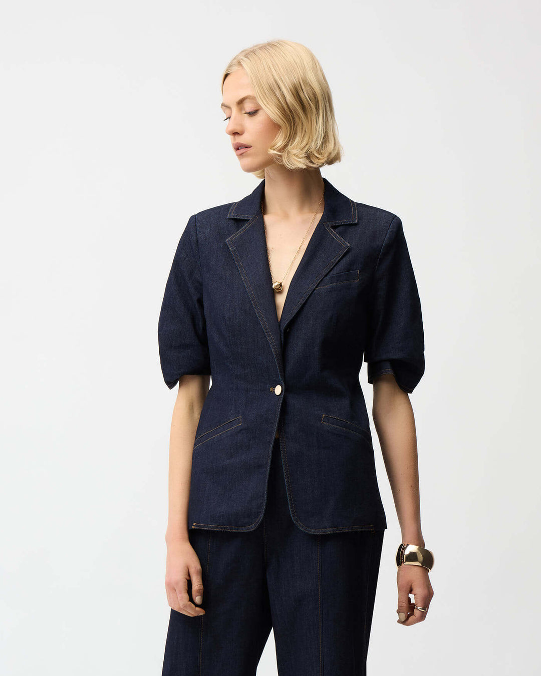 Joseph Ribkoff dark blue denim blazer with gold buttons and cuff tab detail. On a white studio background 