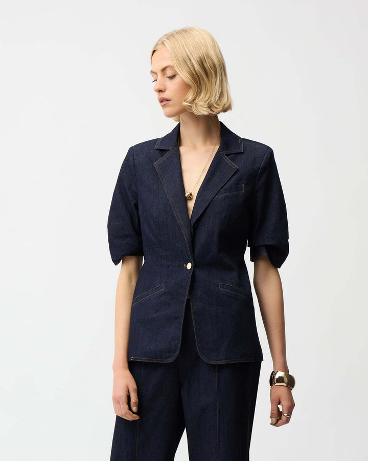 Joseph Ribkoff dark blue denim blazer with gold buttons and cuff tab detail. On a white studio background 
