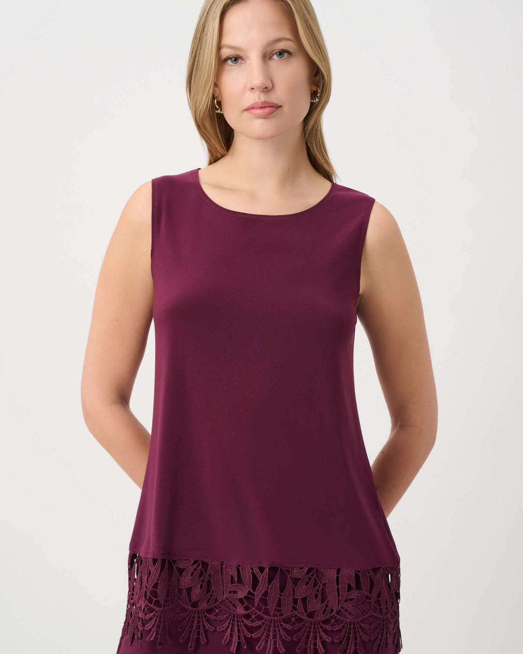 Joseph Ribkoff modeling a sleeveless scoop-neck top in deep burgundy with a matching lace-trimmed hem, paired with matching pants, against a plain light gray studio background.
