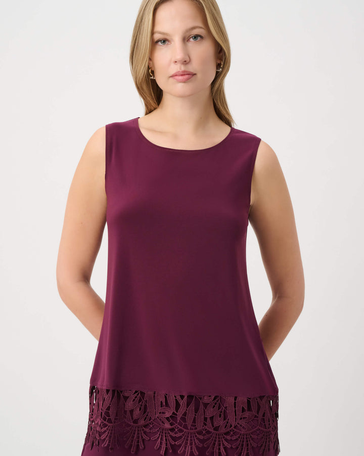 Joseph Ribkoff modeling a sleeveless scoop-neck top in deep burgundy with a matching lace-trimmed hem, paired with matching pants, against a plain light gray studio background.