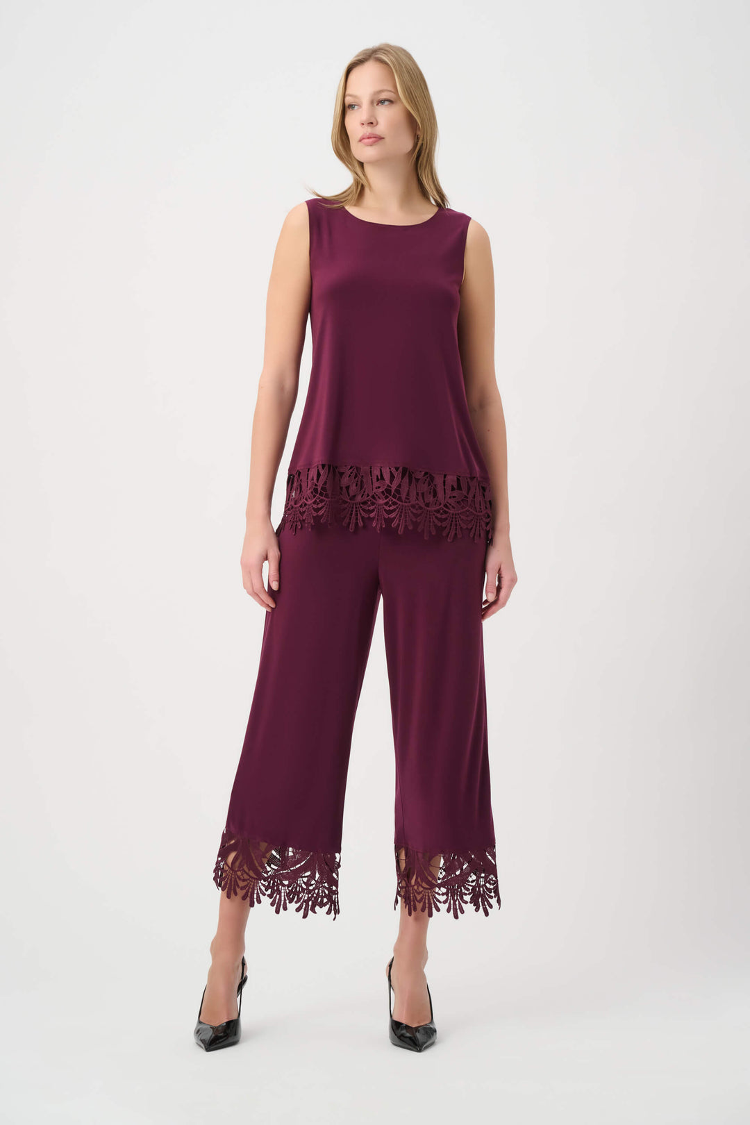 Joseph Ribkoff modeling a sleeveless scoop-neck top in deep burgundy with a matching lace-trimmed hem, paired with matching pants, against a plain light gray studio background.