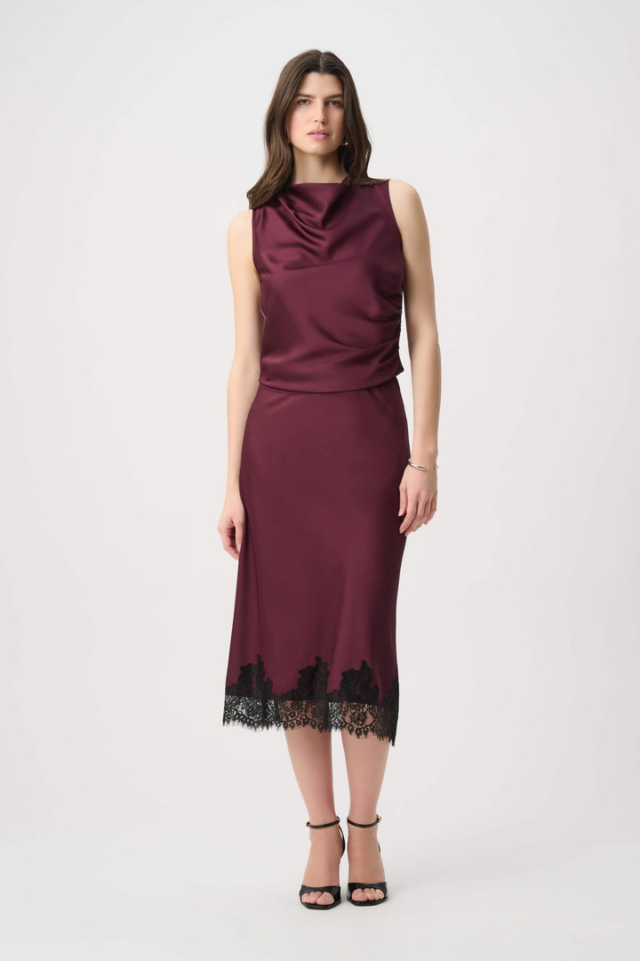 Joseph Ribkoff  modeling a sleeveless, high-neck, draped satin dress in a deep burgundy color against a plain light gray background.