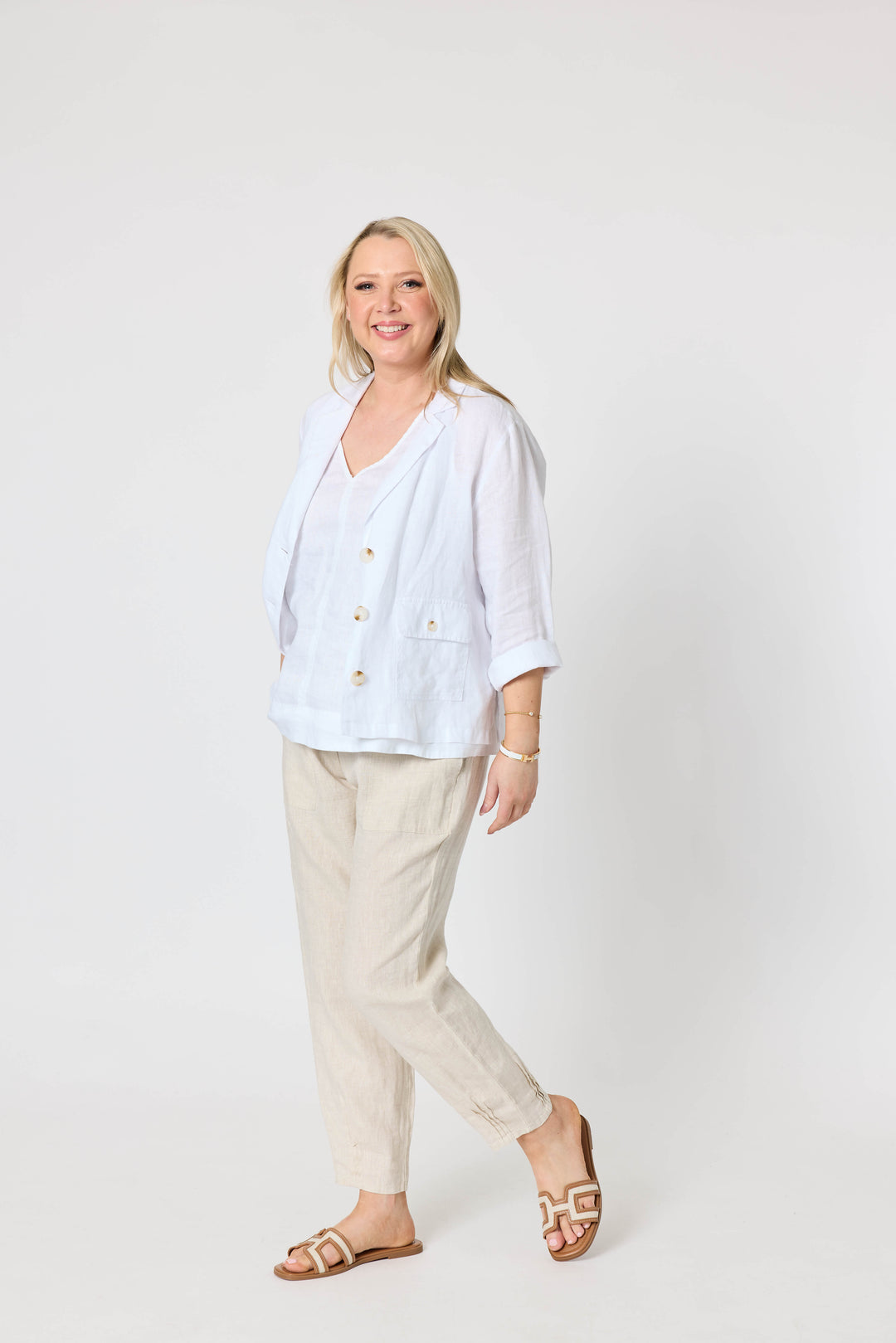 Gordon Smith  modeling a white button-up linen jacket and beige linen trousers, standing against a plain white studio background.
