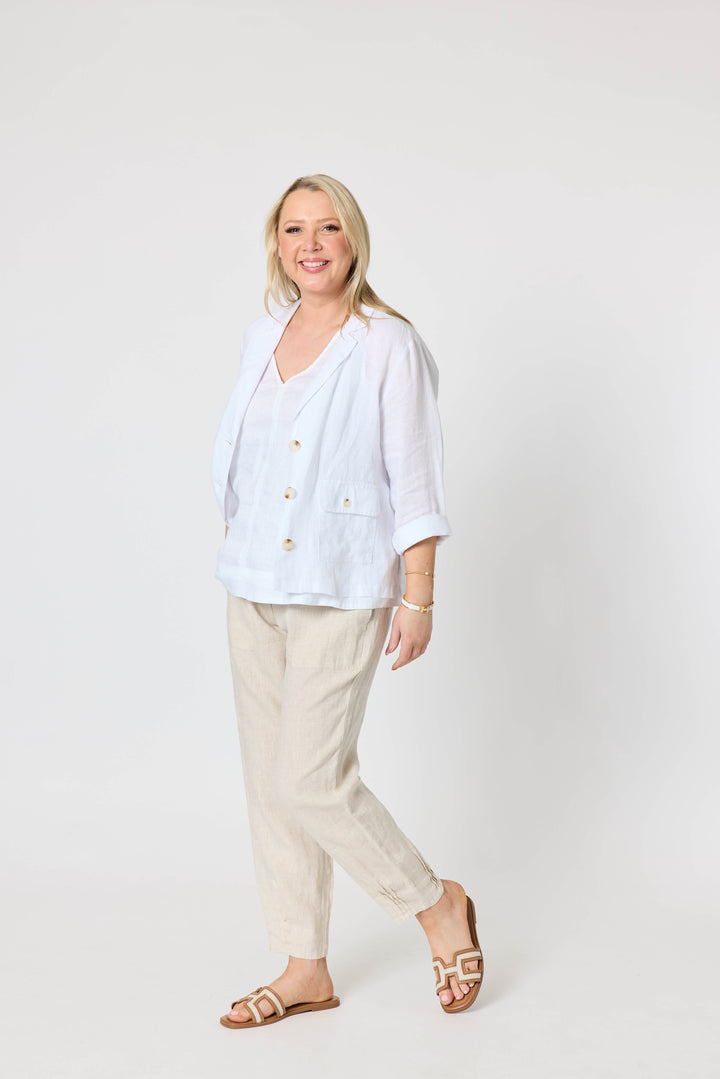 Gordon Smith  modeling a white button-up linen jacket and beige linen trousers, standing against a plain white studio background.