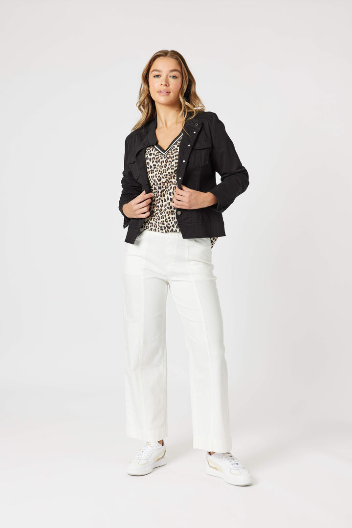 Threadz model modeling a black cropped jacket over a leopard-print top, paired with white wide-leg jeans and white sneakers, against a plain light gray studio background.