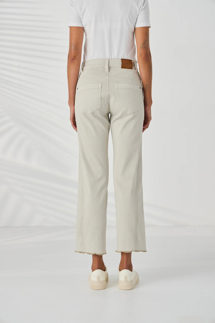 Lania The Label A model is wearing a pair of light beige cropped jeans with gold floral embroidery on the lower legs, paired with a white t-shirt and cream platform sneakers against a white studio background.