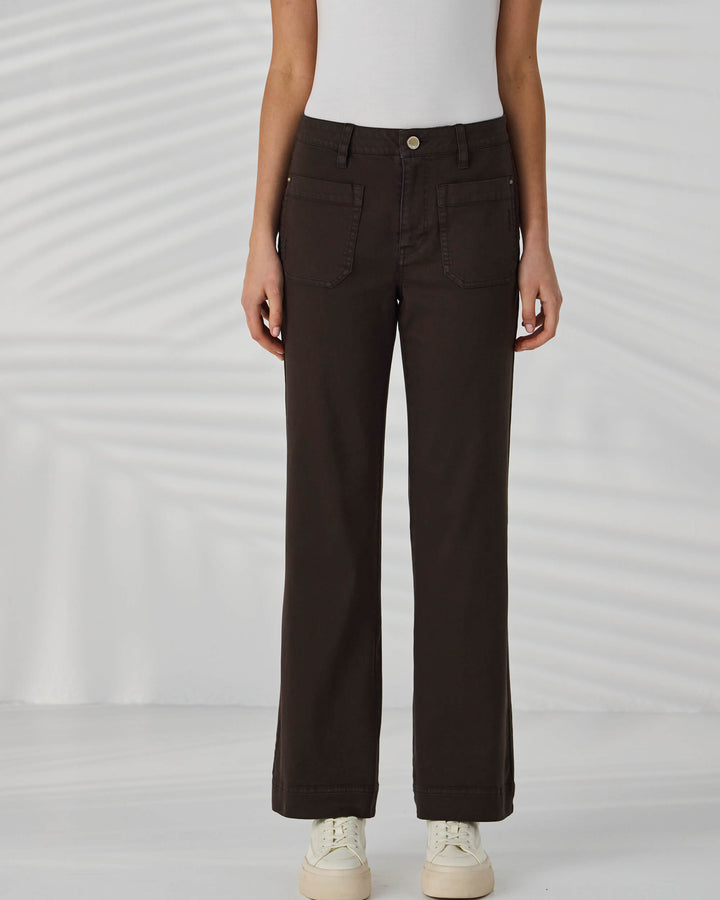 Lania The Label Model wearing black pants and white sneakers on a light gray background
