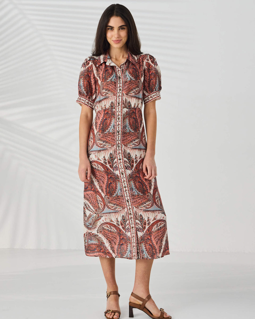 Lania The label model wearing a patterned dress in pinks and blues on a white  studio background.