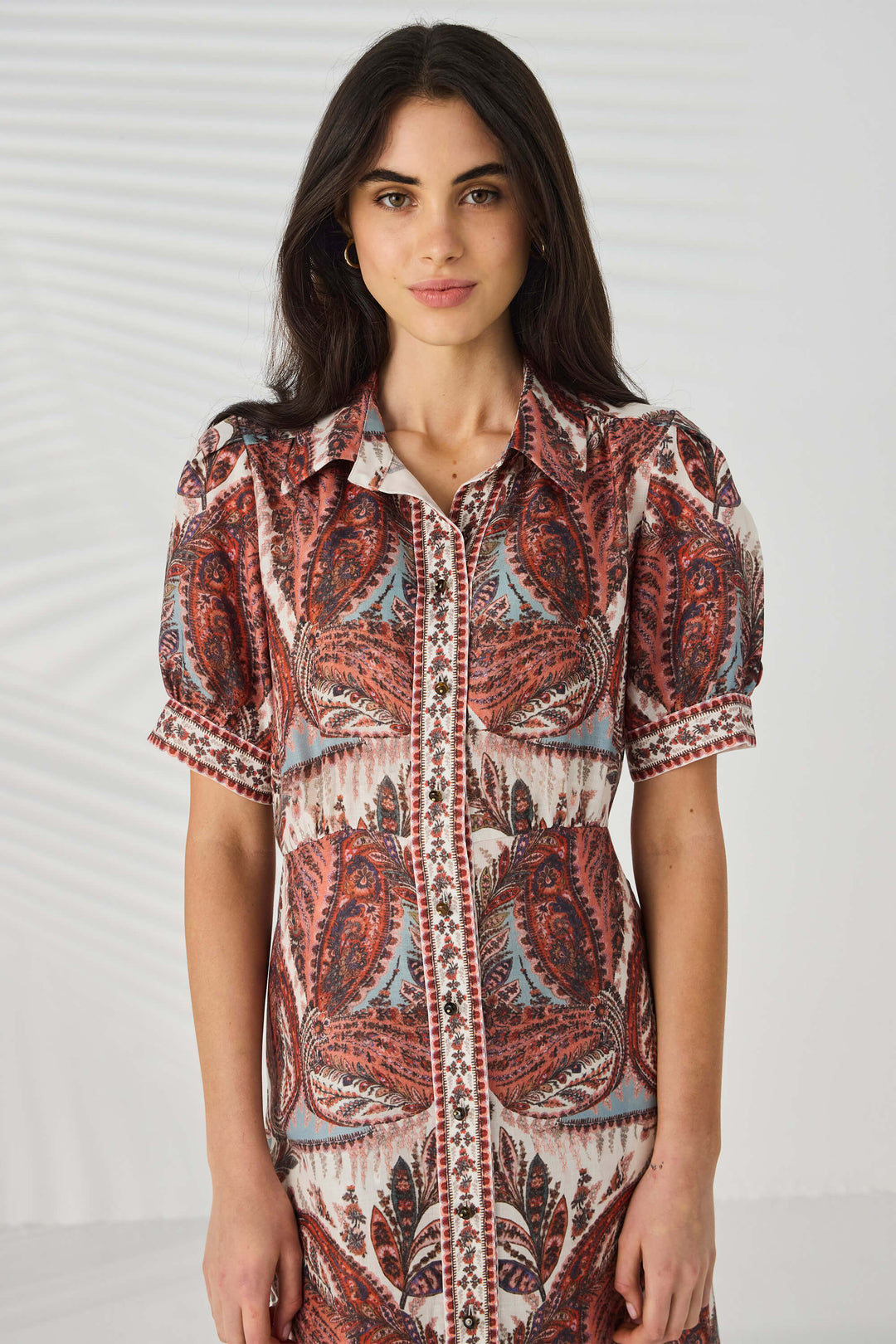Lania The label model wearing a patterned dress in pinks and blues on a white  studio background.