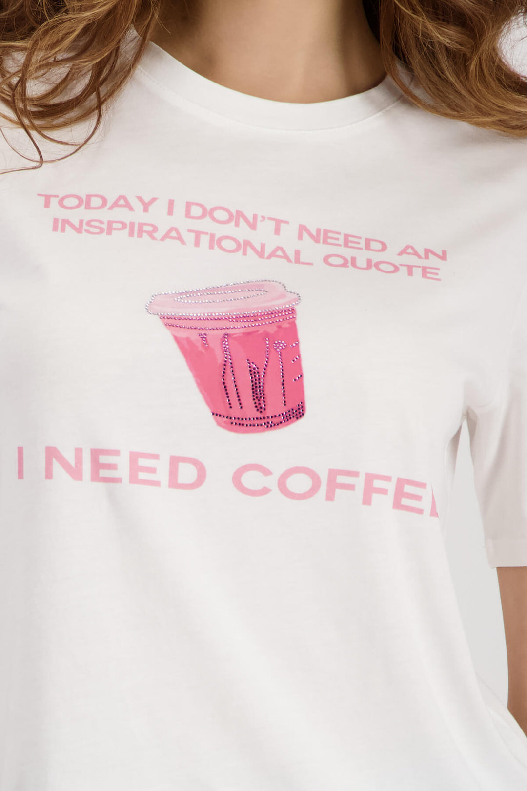 White T-shirt close-up showing pink coffee cup graphic and “I NEED COFFEE”