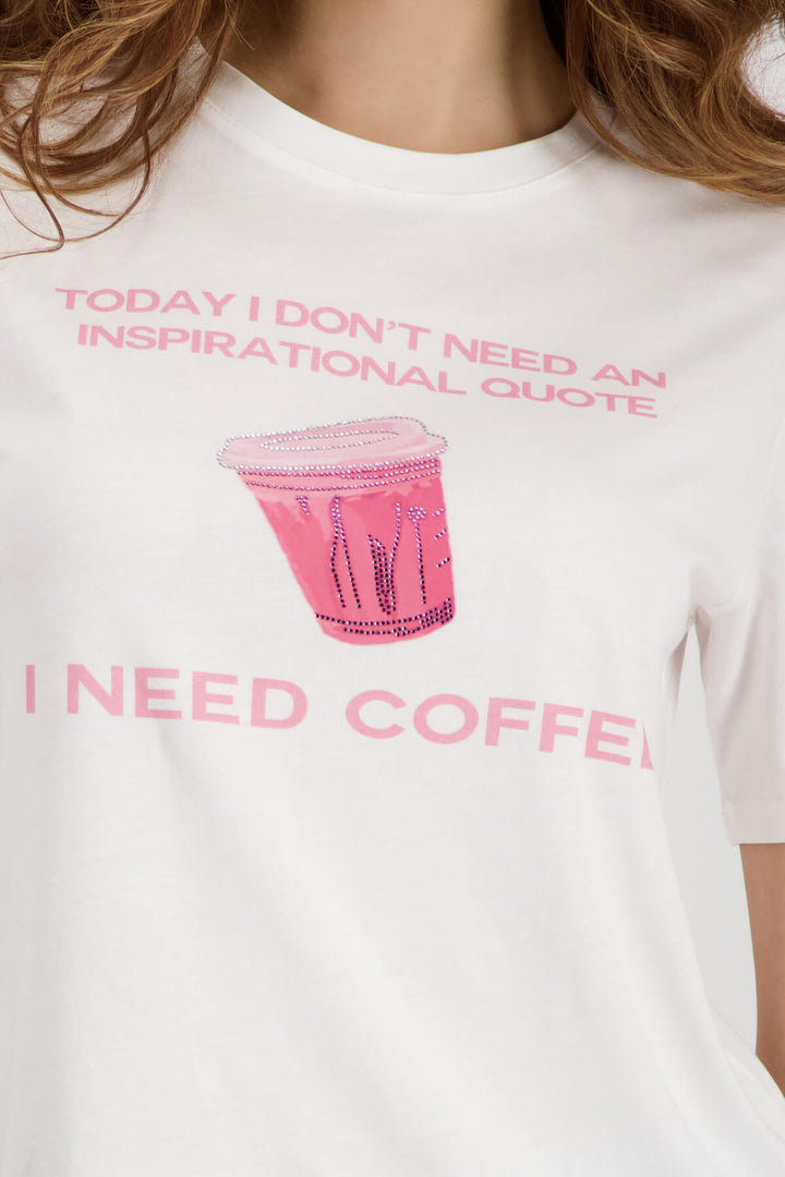 White T-shirt close-up showing pink coffee cup graphic and “I NEED COFFEE”
