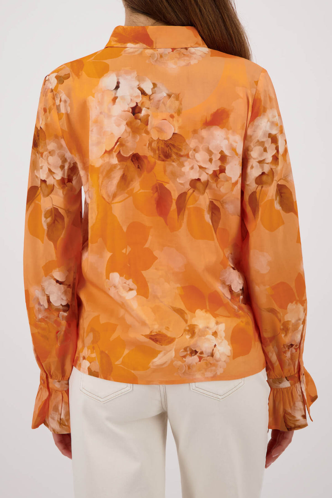 Monari orange tie-dye button-up blouse with pointed collar and long ruffle cuffs on a model with her back to camera