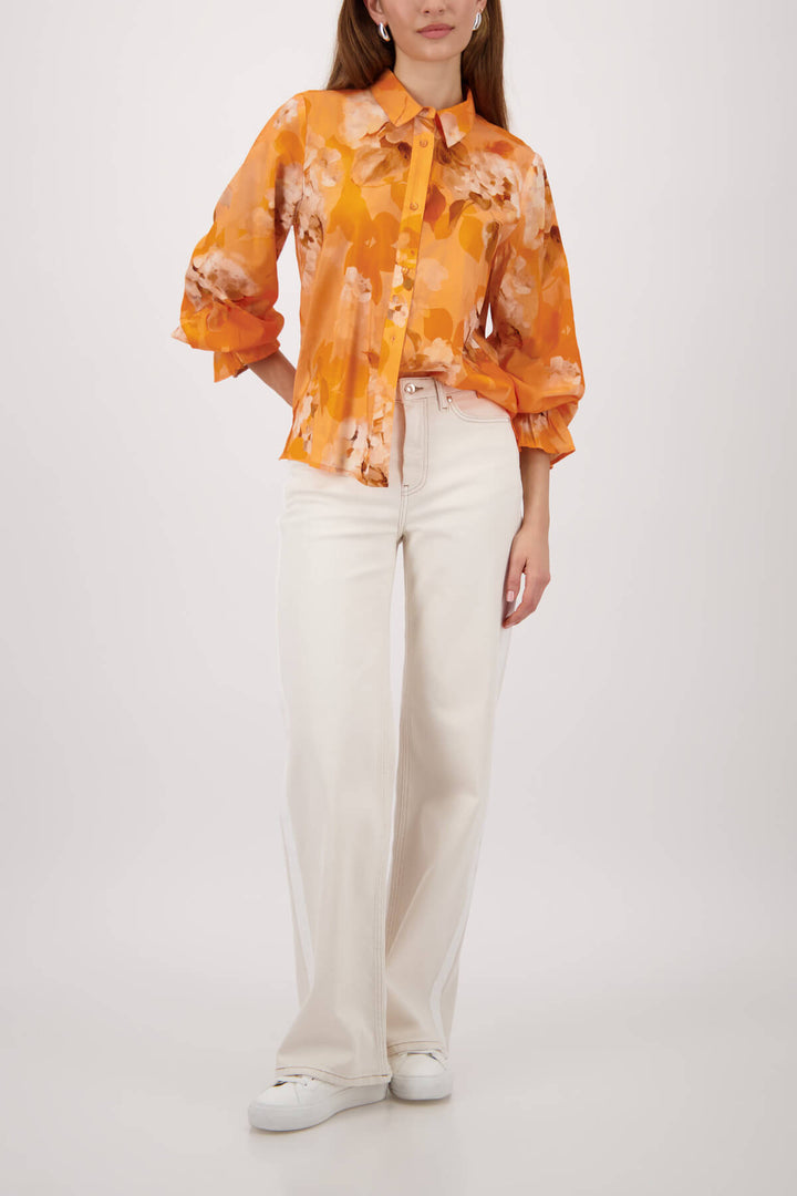 Monari orange tie-dye button-up blouse with pointed collar and long ruffle cuffs on a model