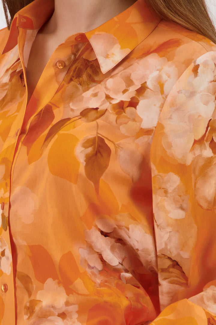 Monari orange tie-dye button-up blouse with pointed collar and long ruffle cuffs on a model