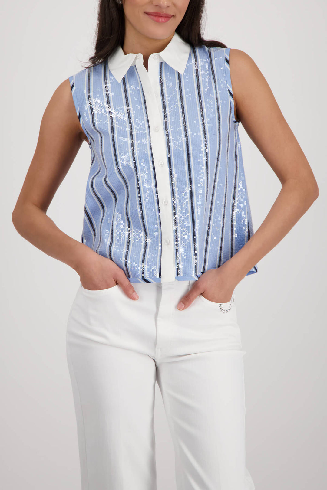 Monari woman modeling a sleeveless button-front top with vertical blue and white stripes, a white collar, and white pants against a light gray studio background.