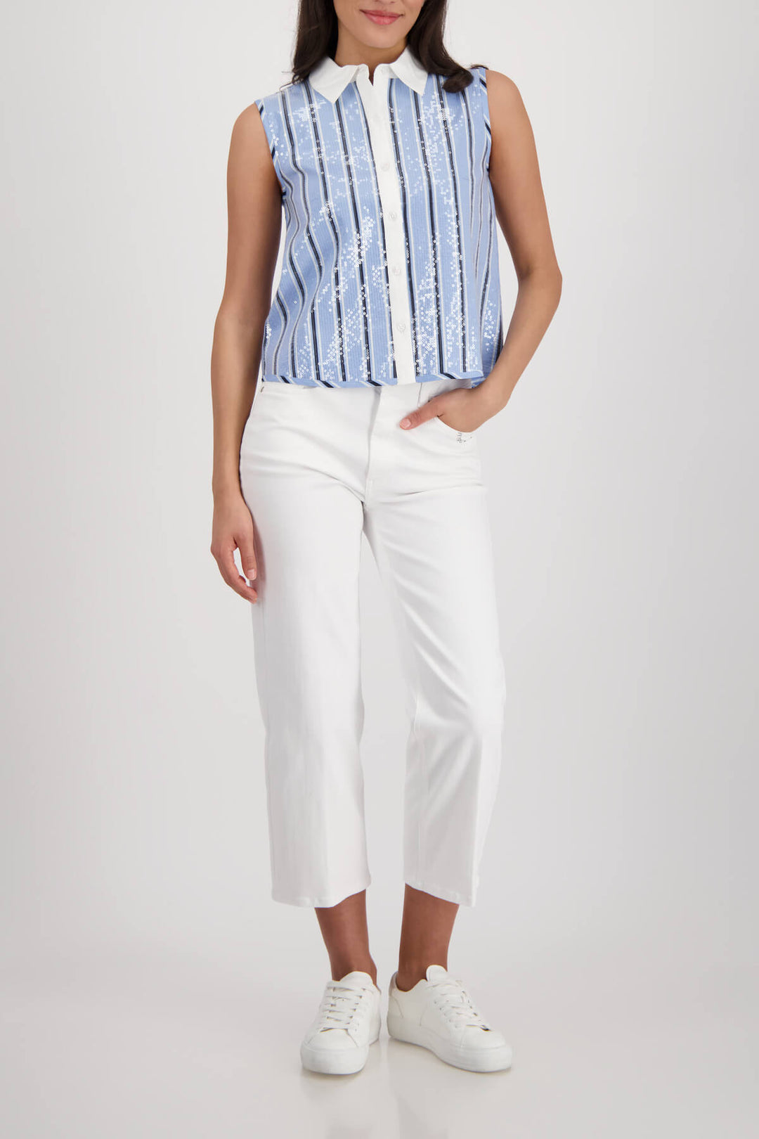 Monari woman modeling a sleeveless button-front top with vertical blue and white stripes, a white collar, and white pants against a light gray studio background.