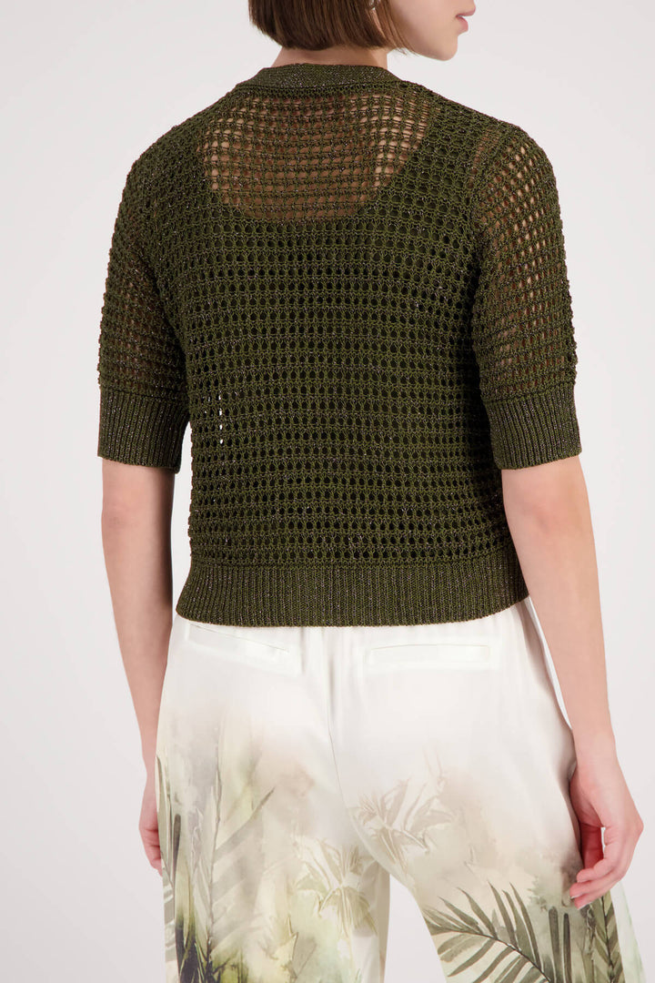 Monari woman modeling a short-sleeve olive green knit cardigan over a matching olive green top, paired with wide-leg white pants featuring a green and beige palm tree print, against a light gray studio background. Back view