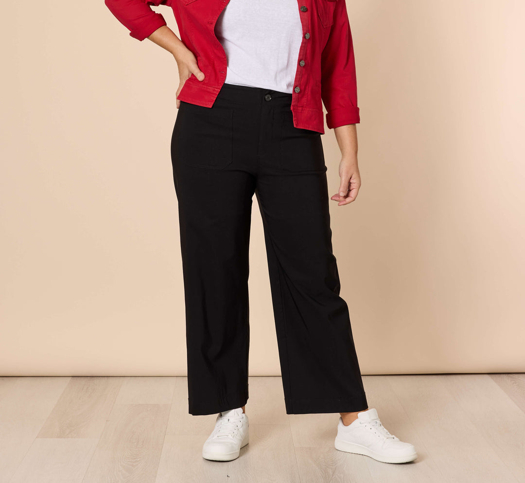Threadz Model A woman modeling a red button-up shirt jacket over a white t-shirt and black wide-leg trousers, standing against a solid beige studio background.