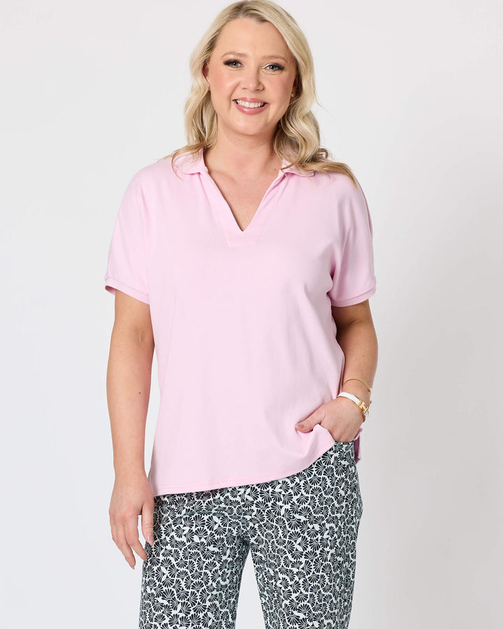 Gordon Smith Model A woman modeling a light pink short-sleeve polo shirt and dark gray and white patterned shorts against a plain white studio background.