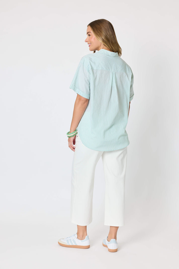Threadz Model A woman modeling a light mint green short-sleeve button-up shirt with colorful embroidered details, paired with white cropped pants and white sneakers, against a plain white studio background.