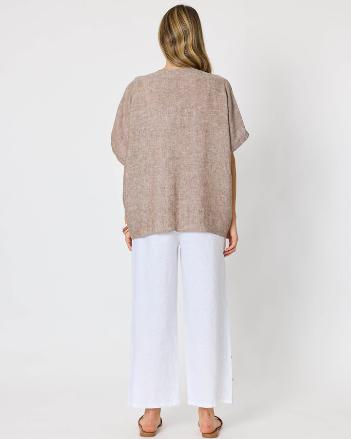 A Hammock &amp; Vine model viewed from behind wearing a loose, short-sleeve taupe knit top and white wide-leg pants against a plain white studio background.