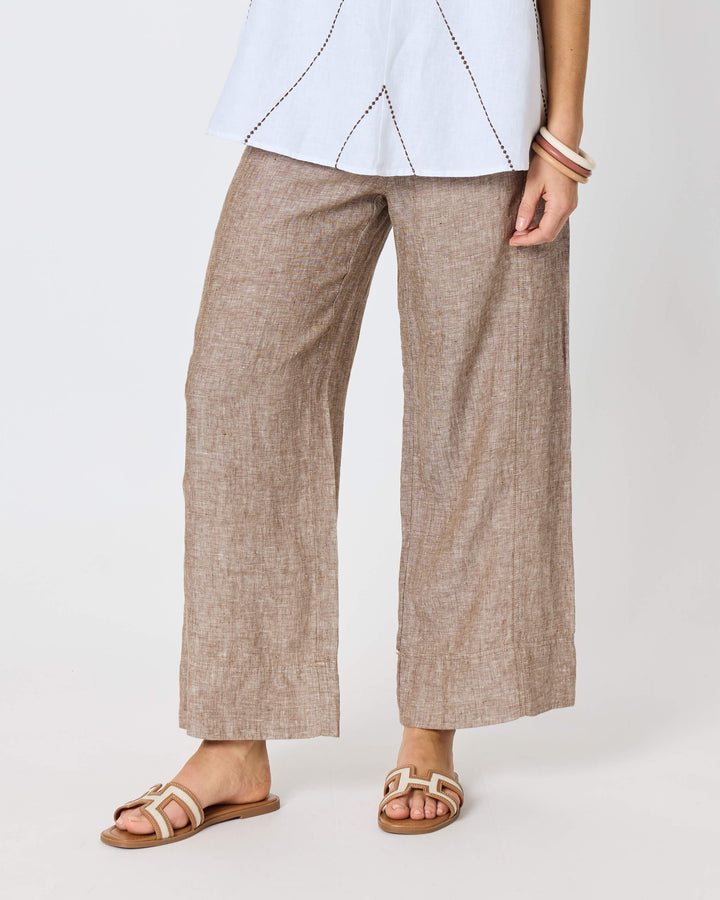 A hammock &amp; vine model wearing a sleeveless white top with thin brown geometric line details and wide-leg taupe pants against a plain white studio background.