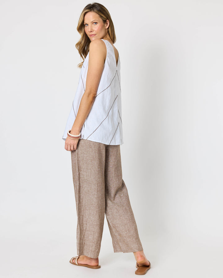 A hammock &amp; vine model wearing a sleeveless white top with thin brown geometric line details and wide-leg taupe pants against a plain white studio background.