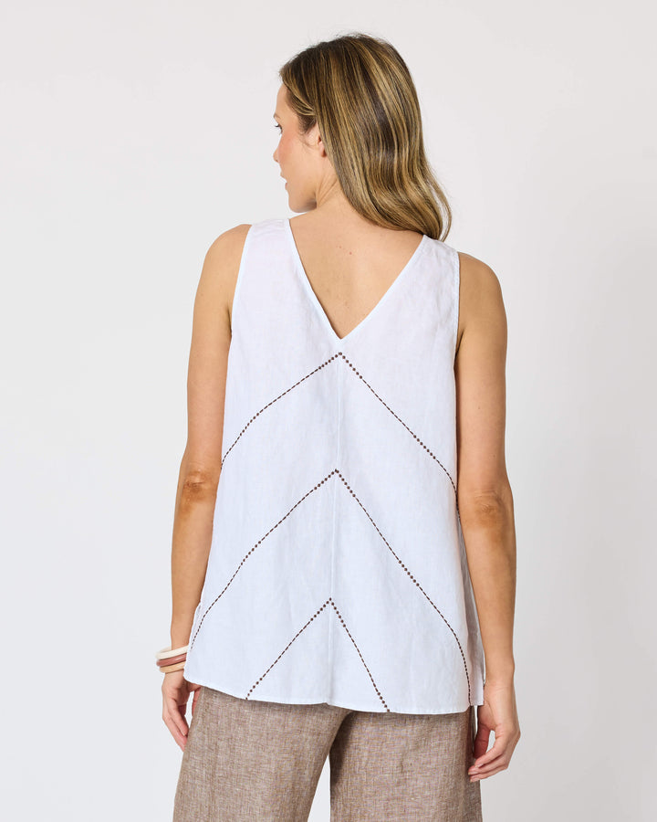 A Hammock &amp; Vine model seen from the back wearing a sleeveless white top with a V-neckline and geometric line pattern, paired with wide-leg taupe pants and flat sandals, against a plain white studio background.