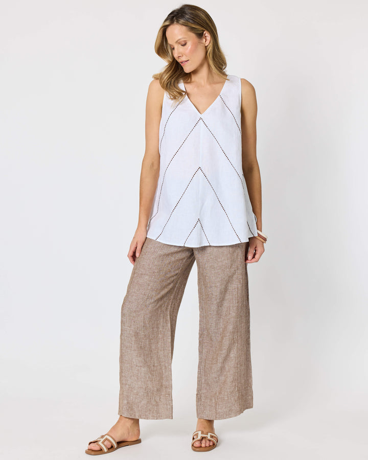A hammock &amp; vine model wearing a sleeveless white top with thin brown geometric line details and wide-leg taupe pants against a plain white studio background.