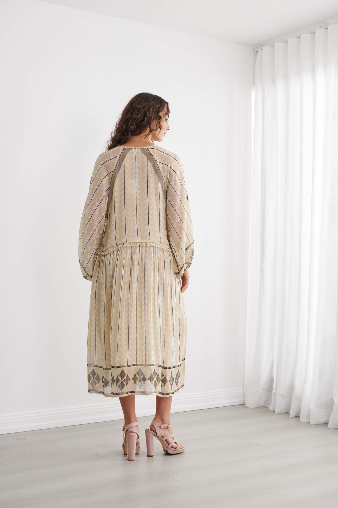Back view of cream Moroccan striped dress with diamond border hem and tassel ties