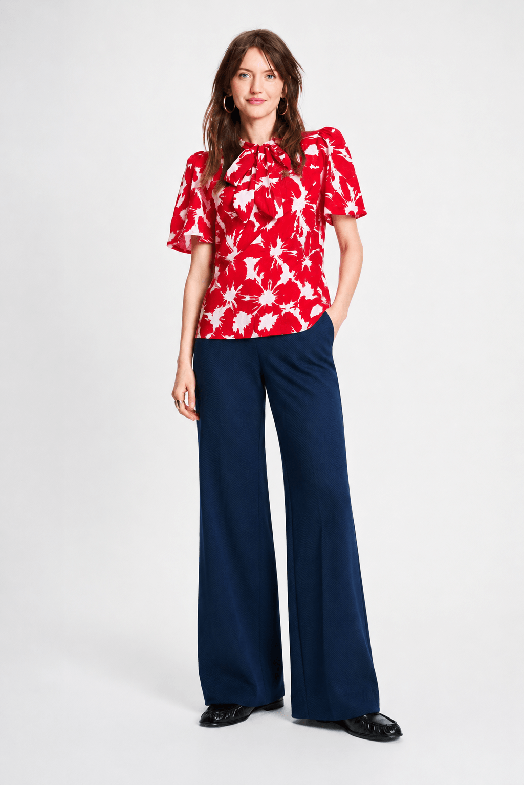 Pom Amsterdam model wearing navy blue wide-leg trousers with a red top partially visible, photographed against a clean white studio background.