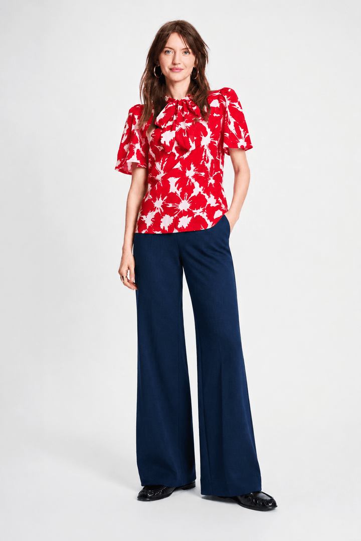 Pom Amsterdam model wearing navy blue wide-leg trousers with a red top partially visible, photographed against a clean white studio background.