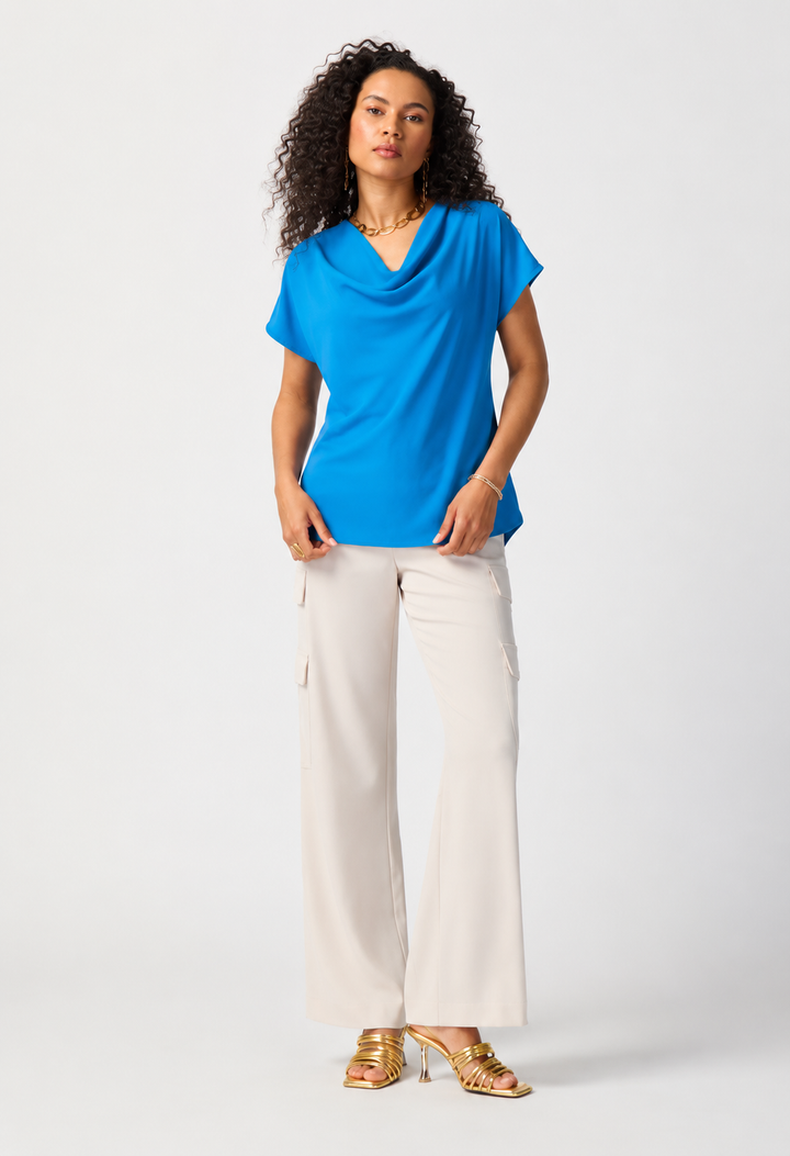 Woman wearing a blue top and white pants on a white background