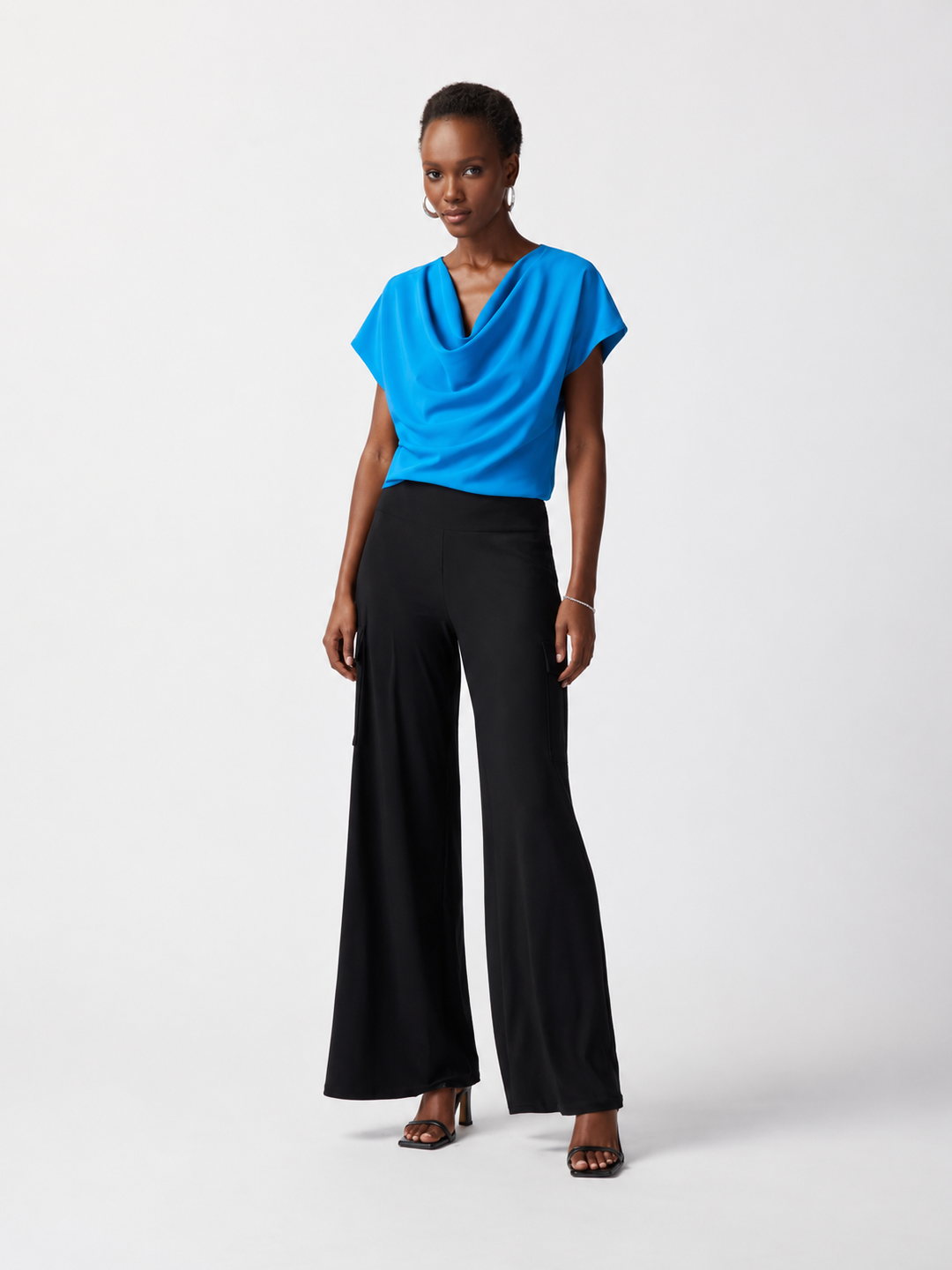 Woman wearing a blue top and black pants on a white background