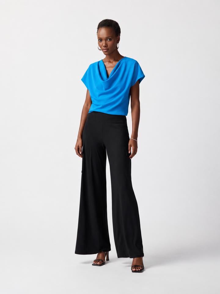 Woman wearing a blue top and black pants on a white background