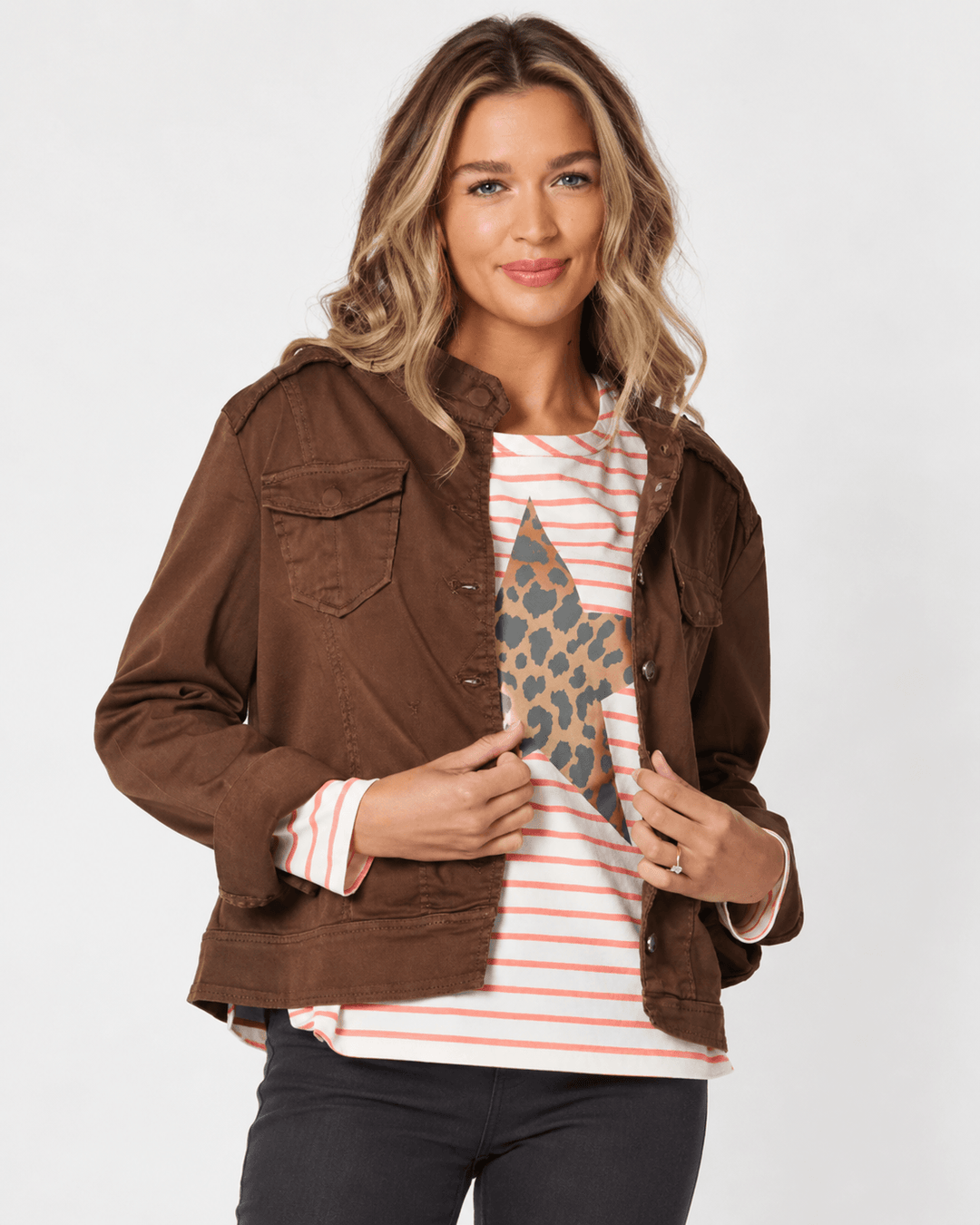 Threadz model in a brown denim military jacket with roll-tab sleeves and buttoned chest pockets on a white background 