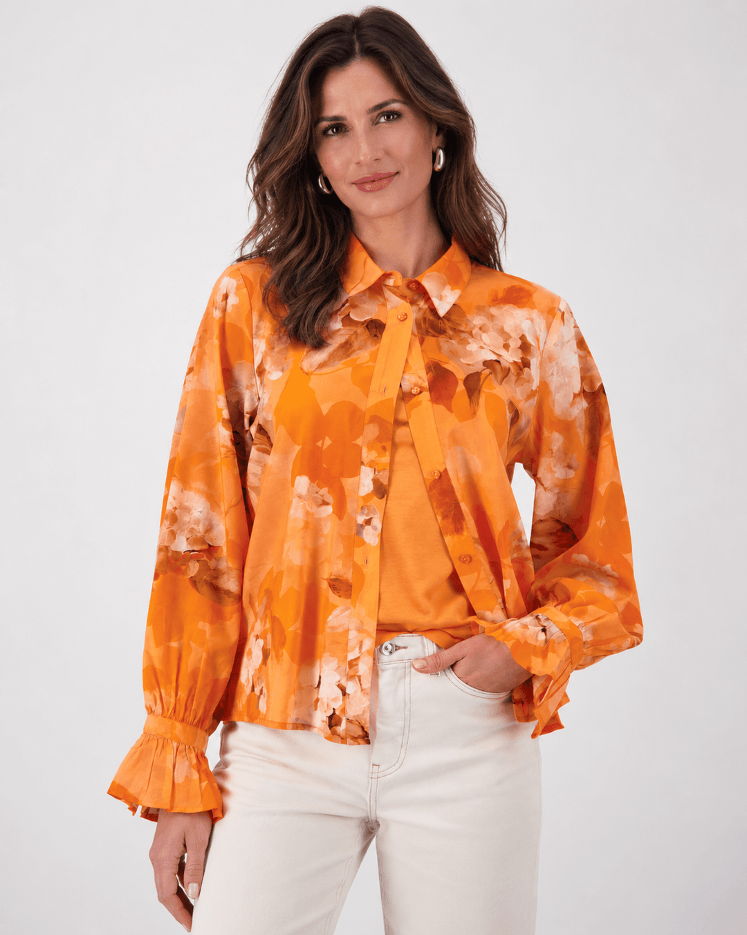 Monari orange tie-dye button-up blouse with pointed collar and long ruffle cuffs on a model. On white studio background.background