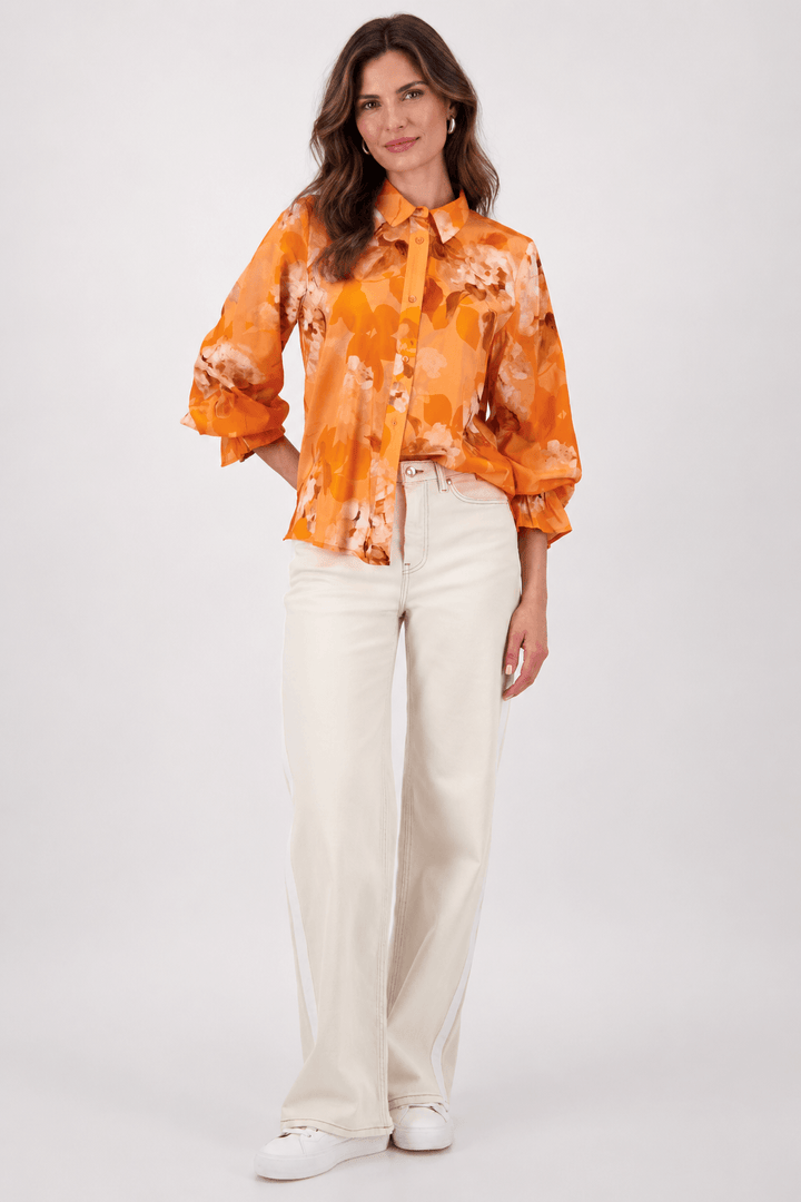 Monari orange tie-dye button-up blouse with pointed collar and long ruffle cuffs on a model. On white studio background.background