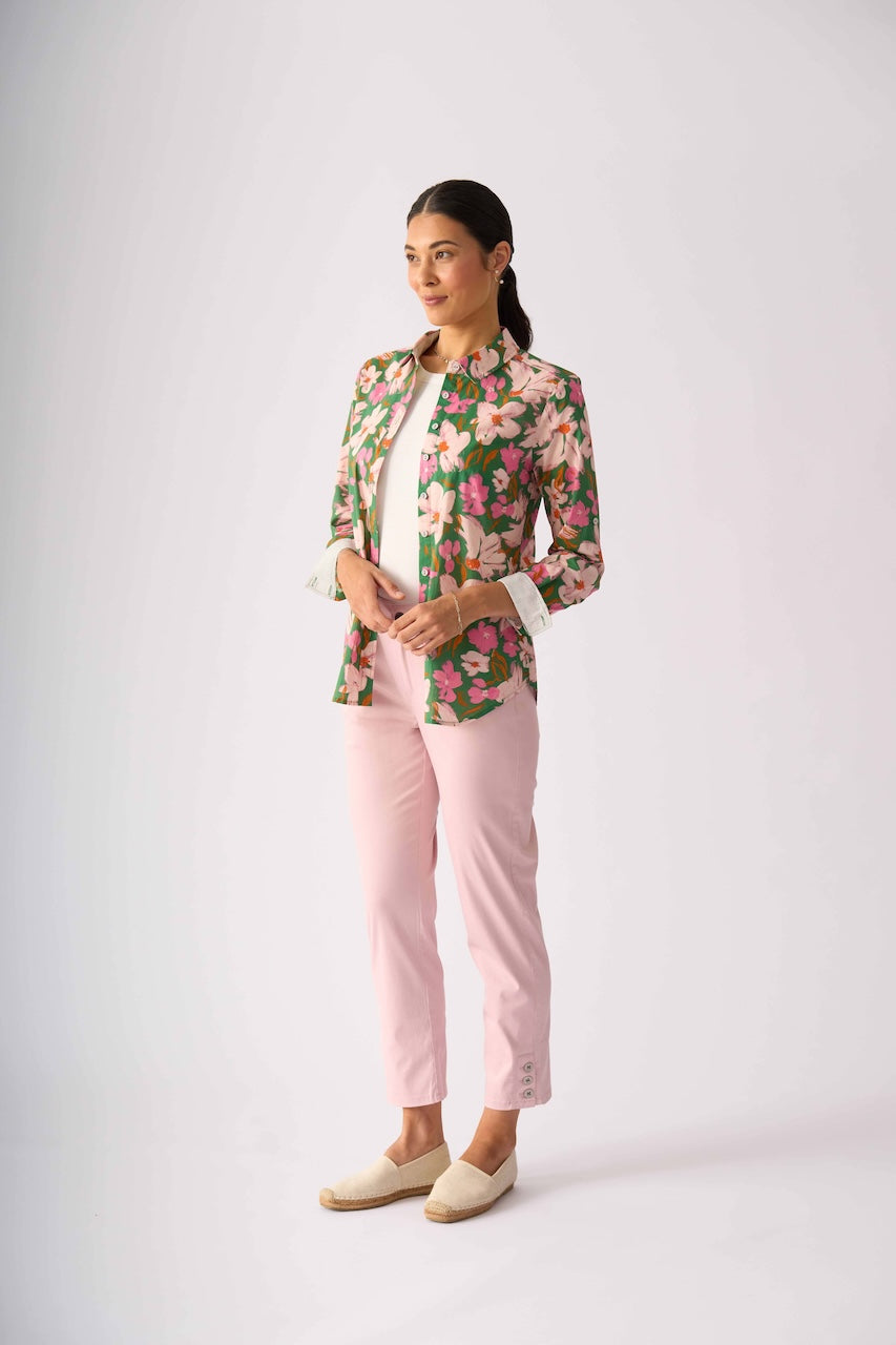 Foil model stands against a light gray studio background wearing a floral button-up shirt with pink and green tones, light pink pants, and beige slip-on shoes.