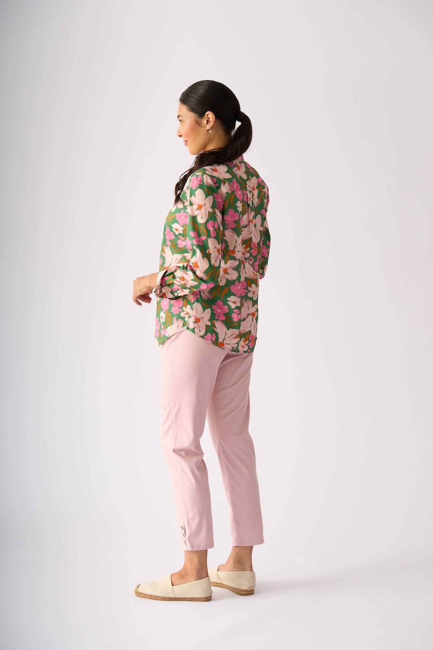 Foil model stands against a light gray studio background wearing a floral button-up shirt with pink and green tones, light pink pants, and beige slip-on shoes.
