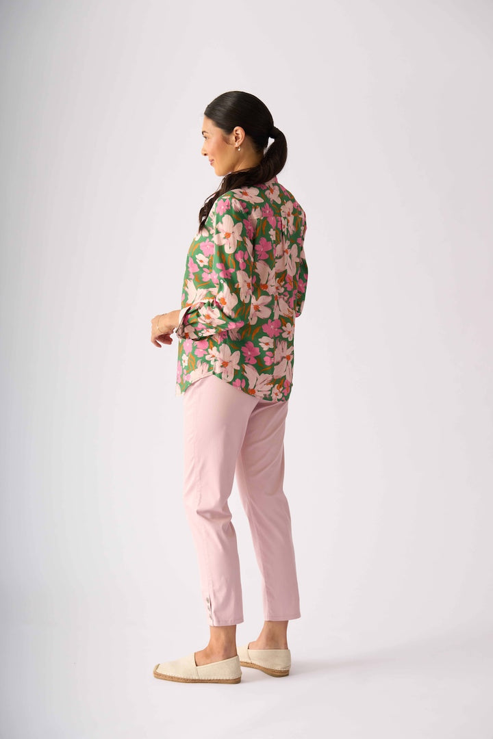 Foil model stands against a light gray studio background wearing a floral button-up shirt with pink and green tones, light pink pants, and beige slip-on shoes.